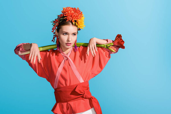 beautiful elegant girl in wreath holding living coral flower isolated on blue. Pantone color of the year 2019 concept