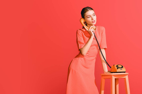 fashionable woman with vintage rotary phone isolated on living coral. Pantone color of the year 2019 concept