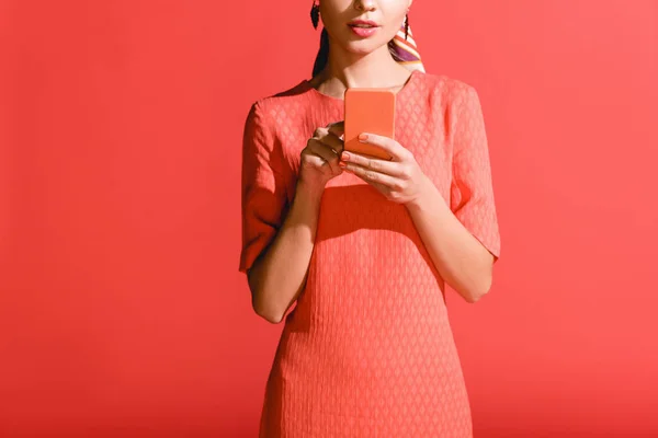 裁剪的妇女在活珊瑚礼服使用智能手机在红色 2019年的潘通颜色概念 — 图库照片