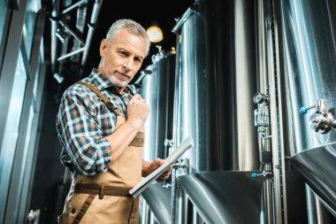 Erkek bira bira fabrikasında not defteri tutan iş yarı tulumlar içinde