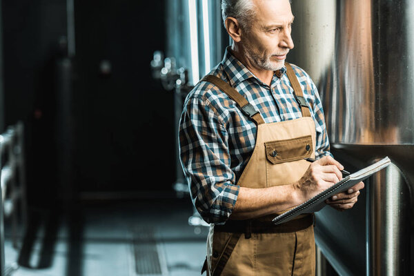 профессиональный пивовар в блокноте на пивоваренном заводе
