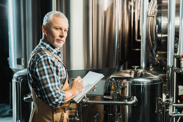 Cervecero Masculino Senior Escribiendo Bloc Notas Mientras Revisa Equipo Cervecería — Foto de Stock