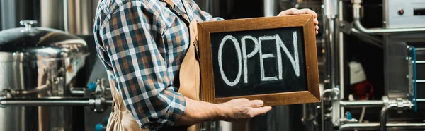 cropped view of owner holding board with open sign in brewery