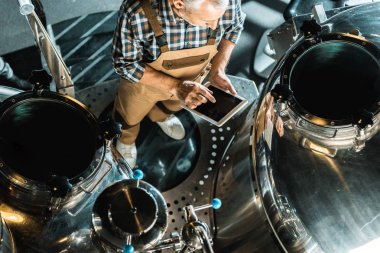 Dijital tablet kullanma ve bira fabrikasında çalışan erkek brewer havai görünümü
