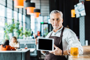 üst düzey sahibi pub bardak bira ile dijital tablet boş ekran ile tutarak önlük