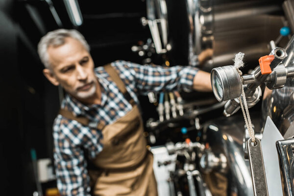 selective focus of professional male brewer working with brewery equipment