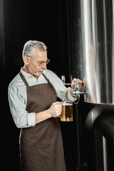красивый старший пивовар разливает пиво для тестирования на пивоваренном заводе
