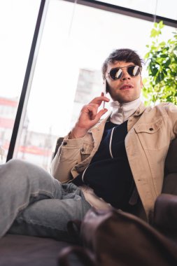 trendy adam smartphone kafede konuşurken güneş gözlüğü