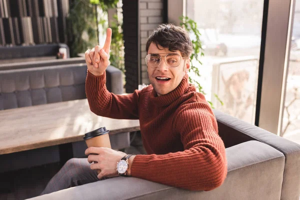 紙コップを押しながらカフェで身振りで示すガラスの幸せな男 — ストック写真