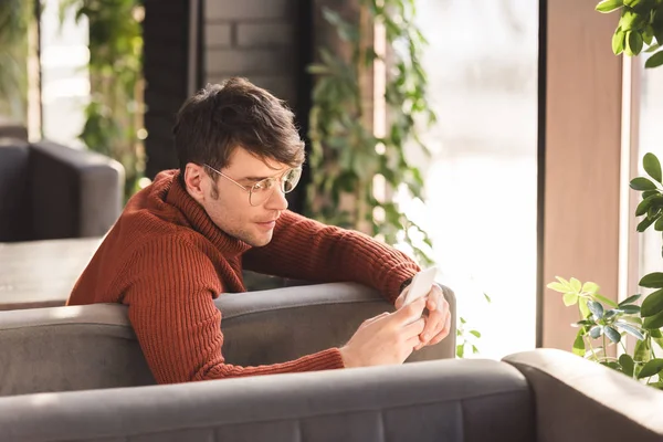 Ernstige Jonge Man Glazen Gebruikend Smartphone Zittend Café — Stockfoto