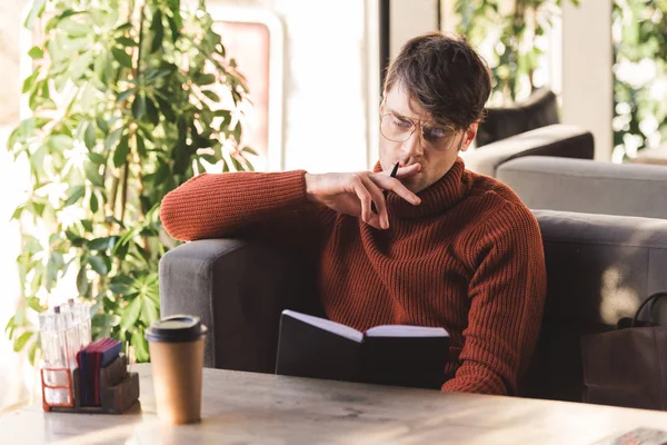 Uomo Premuroso Bicchieri Tenendo Penna Mentre Guardando Notebook Vicino Tazza — Foto Stock