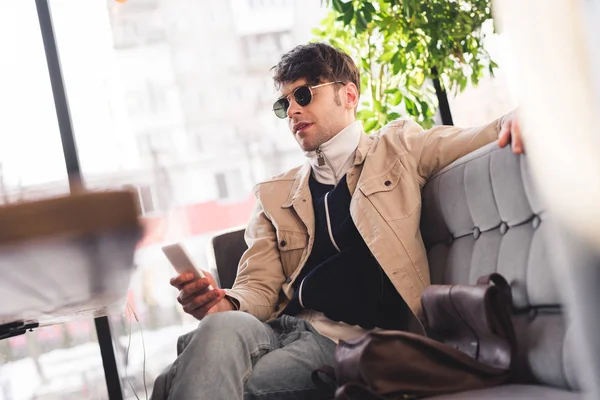 Uomo Elegante Occhiali Sole Che Tiene Smartphone Mentre Siede Caffè — Foto Stock