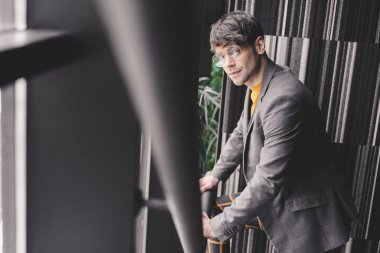 yakışıklı ve trendy genç adam merdivenlerde durup gözlüklü  