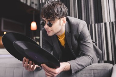 stylish young man in sunglasses looking at retro vinyl records clipart