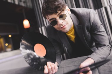 handsome young man in sunglasses looking at retro vinyl records clipart