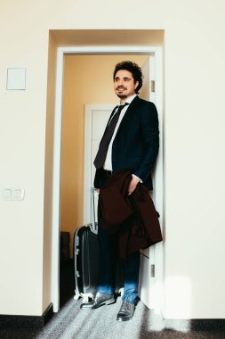 Takım elbiseli işadamı ile otel odasında seyahat çantası