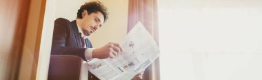 güneş ışığı ile otel odasında gazetede takım elbiseli yakışıklı işadamı