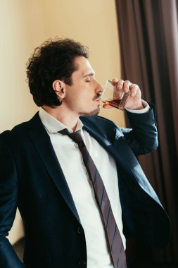 işadamı cam otel odasında viski içme takım elbiseli 