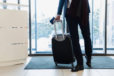 Otele gelen pasaport ve seyahat çantası ile işadamı kırpılmış görünümü 