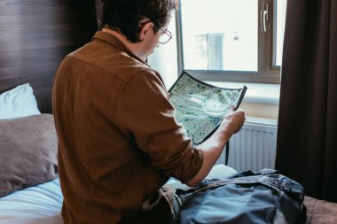 Arkadan erkek turist otel odasında harita bakarak görünüşü