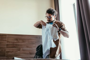 erkek turist otel odasında sırt çantası içine gömlek koyarak gözlük