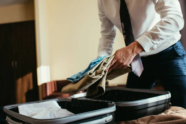旅行バッグに服を置くビジネスマンのトリミング ビュー — ストック写真