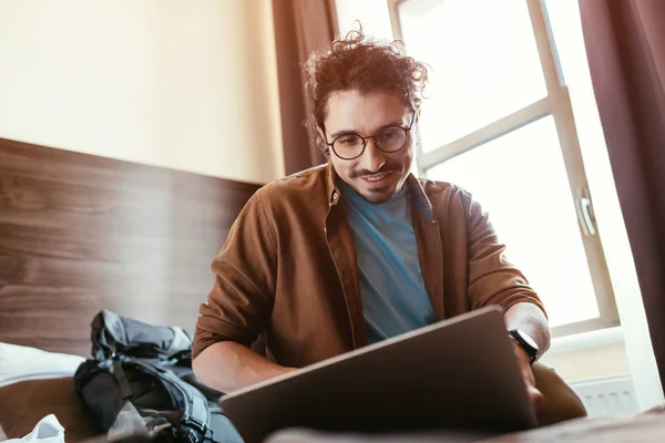 Усміхнений Чоловік Мандрівник Використовує Ноутбук Готельному Номері Рюкзаком — стокове фото