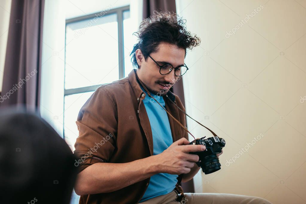 man in eyeglasses looking at photo camera in hotel room