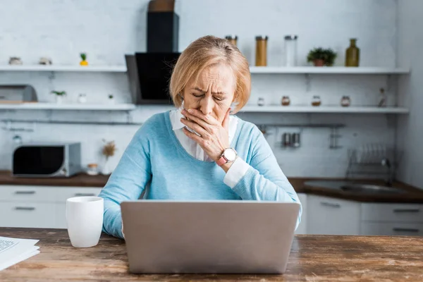 Zdenerwowana Kobieta Senior Obejmujące Usta Ręką Pomocą Laptopa Konieczności Rozmowy — Zdjęcie stockowe