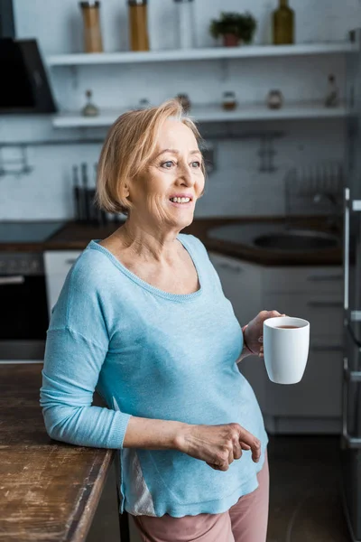 Mujer Mayor Sonriente Con Taza Café Mirando Casa — Foto de Stock