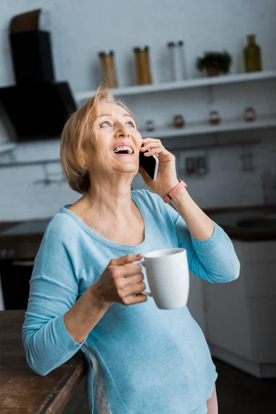 Rindo Mulher Sênior Com Xícara Café Falando Smartphone Casa — Fotografia de Stock