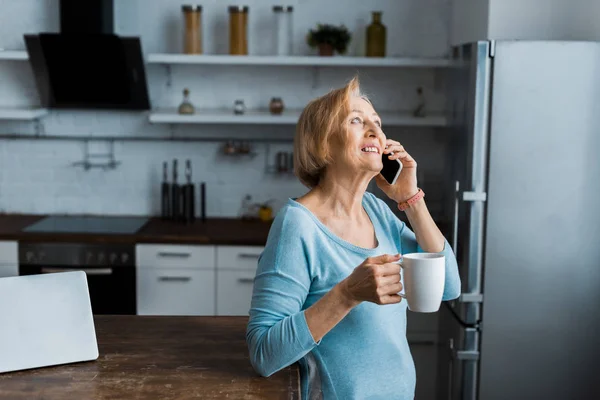 Mujer Mayor Sonriente Con Taza Café Hablando Teléfono Inteligente Casa — Foto de Stock