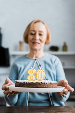 '80' işareti ile pasta üstüne doğum günü kutlaması sırasında tutan üst düzey kadın