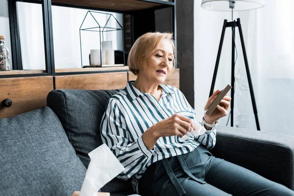 Traurige Seniorin Sitzt Mit Gewebe Und Weint Beim Betrachten Des — Stockfoto