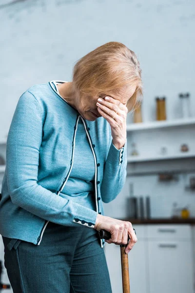 家で泣きの手で顔を覆って 杖を保持している年配の女性のうつ病 — ストック写真