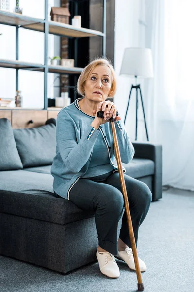 Sad Senior Woman Sitting Couch Holding Walking Stick Home — Stock Photo, Image