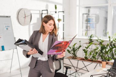 klasörleri tutarak ve Office dururken dergi okuma güzel iş kadını 