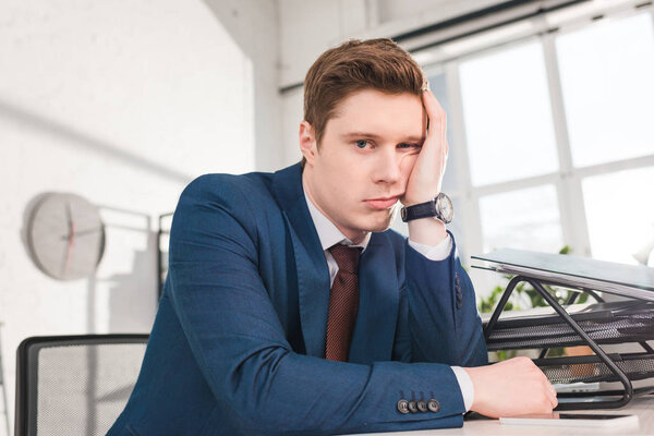 bored businessman sitting and looking at camera in office 