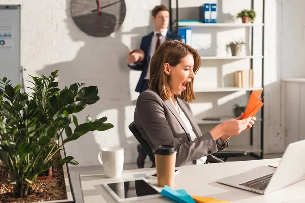 Tired Businesswoman Holding Paper Plane Yawning Laptop Coworker Background Procrastination — Stock Photo, Image