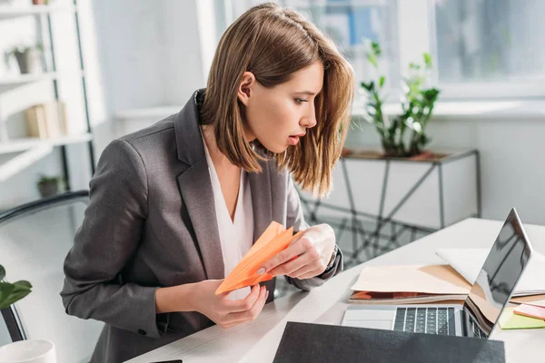 Selective Focus Surprised Businesswoman Holding Paper Plane Looking Laptop Disposable — Stock Photo, Image