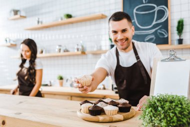 yakışıklı barista kahve evde çalışma cupcake wile kasiyer veren seçici odak