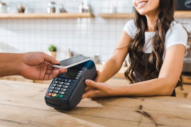 kırpılan yakınındaki bar counter kahverengi önlük ayakta ve smartphone coffee House ile ödeme terminal wile adam tutarak kasiyer görünümünü