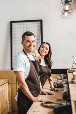 ayakta ve ahşap bar counte coffee House arkasında gülümseyen kasa