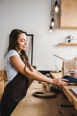 kahverengi önlük ayakta ve smartphone coffee House ile ödeme terminal wile adam tutarak çekici kasiyer