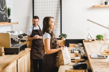 kağıt torba ile çekici kasiyer ve barista sayaç coffee House bar arkasında duran smartphone ile seçici odak