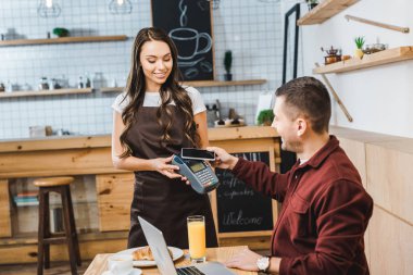 laptop ile masada oturan ve smartphone coffee House ile ödemek cazip garson holding terminal wile yakışıklı serbest meslek