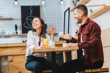 cam suyu ve yakışıklı adam oturmuş ve tablo coffee House gülüyorsun Kupası ile çekici esmer kadın