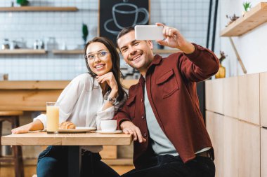 çekici esmer kadın ve tablo ve alma selfie coffee House Smartphone'a oturan bordo tişörtlü yakışıklı adam