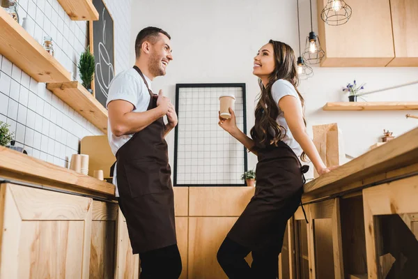 Cashier Holding Paper Cup Talking Barista Brown Apron Wooden Bar — Stock Photo, Image