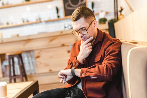 Handsome Man Burgundy Shirt Black Jeans Sitting Couch Looking Watch — Stock Photo, Image